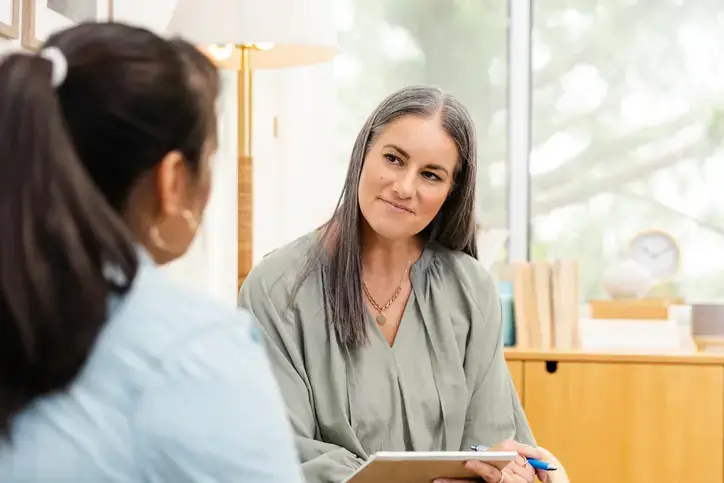The mature adult female therapist has a compassionate, non-judgmental look on her face