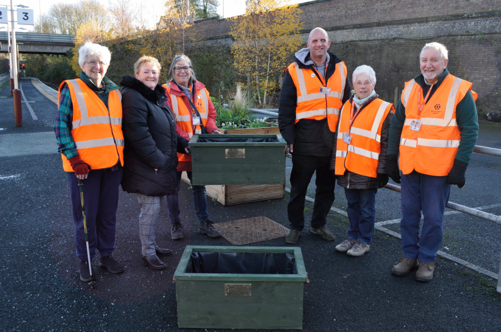 Friends of Wellington Station members Kath Howard, Cllr Julie Pierce, Antony Hook (chair), Kath Padgett, David Bunn, and construction lecturer Angela Pitchford present the planters