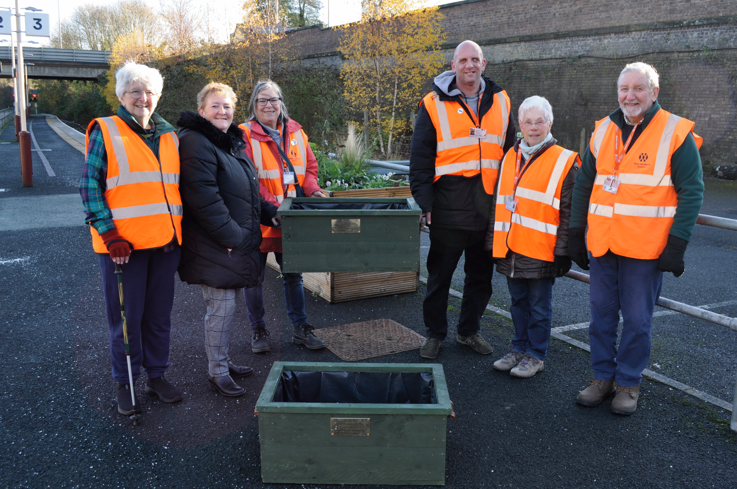 Friends of Wellington Station members Kath Howard, Cllr Julie Pierce, Antony Hook (chair), Kath Padgett, David Bunn, and construction lecturer Angela Pitchford present the planters
